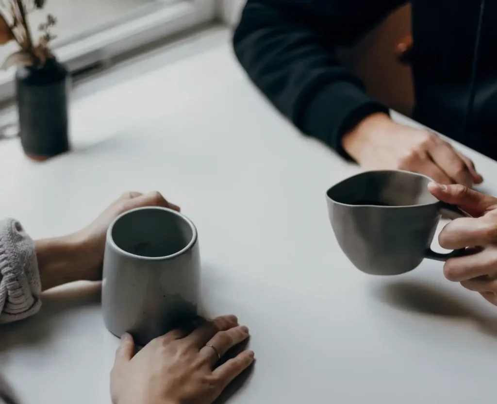 Two people talking over coffee during a private consultation