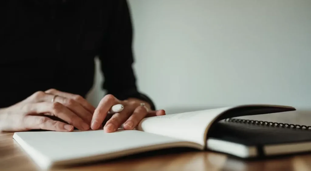 Person writing notes in a journal for reflection and personal development