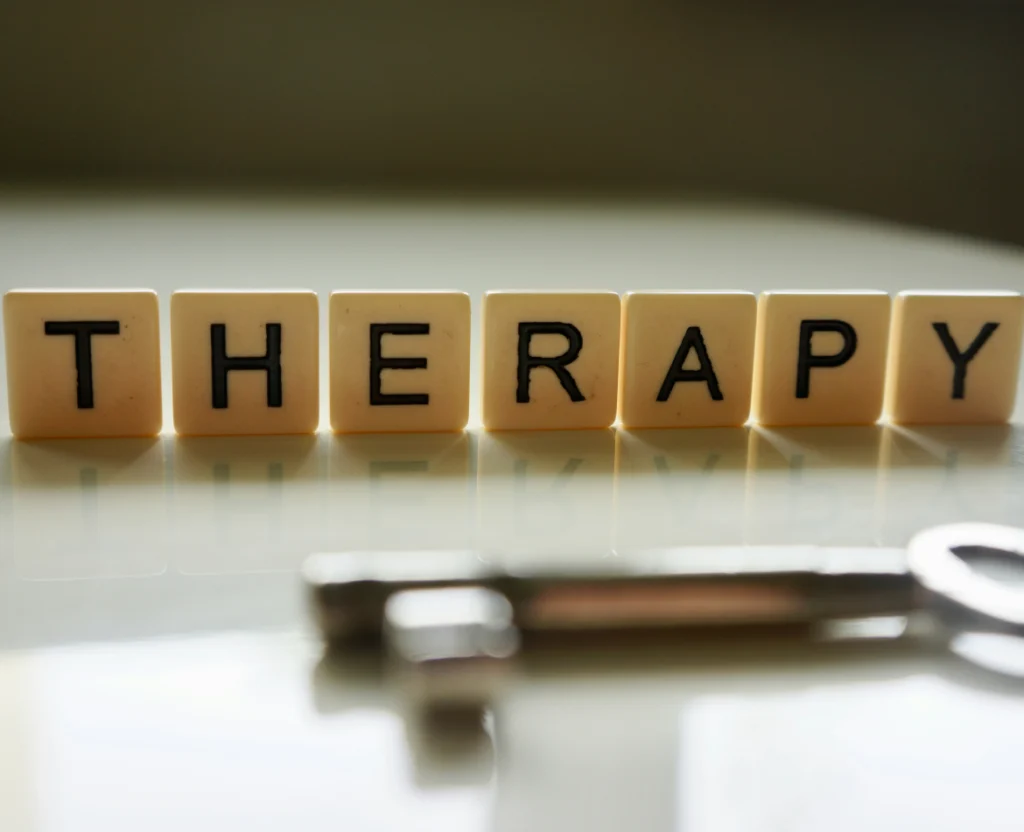 Letter tiles spelling therapy with a key in the foreground, representing access to private mental health support