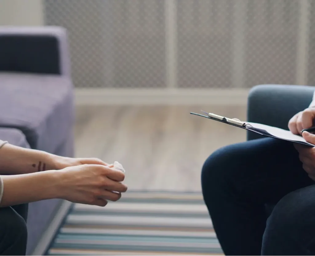 Therapist taking notes while supporting a client during a private home visit therapy session