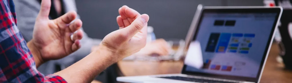 Professional using hand gestures during a discussion beside a laptop