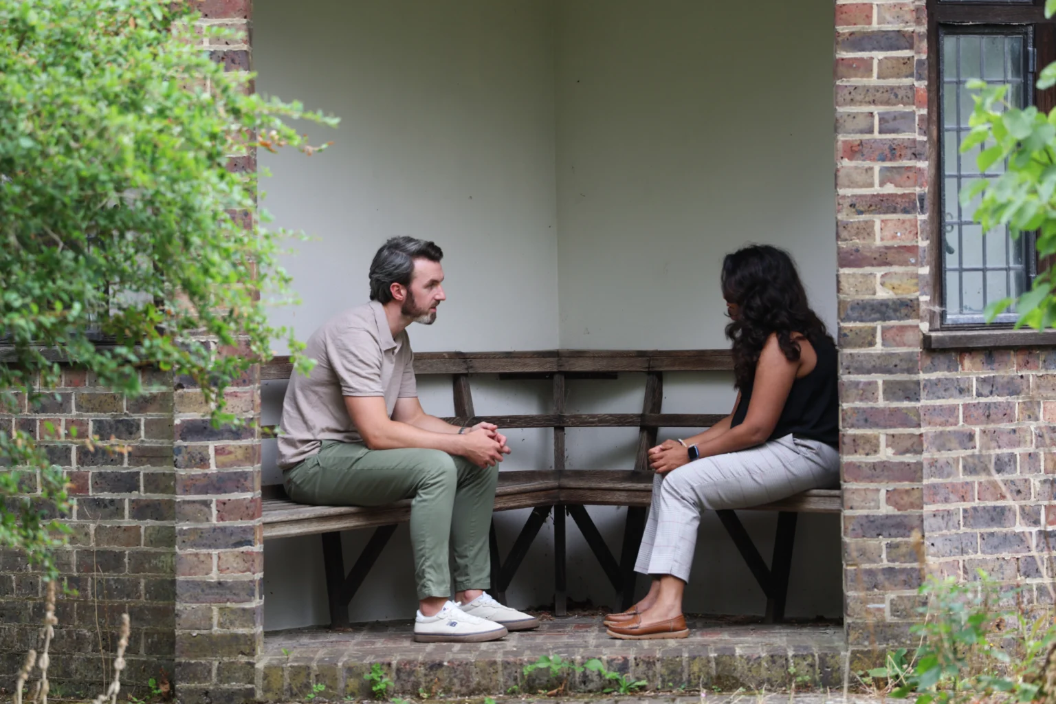 Ryan Hegarty speaking with a client on a garden bench during a compassion focused therapy session in Essex