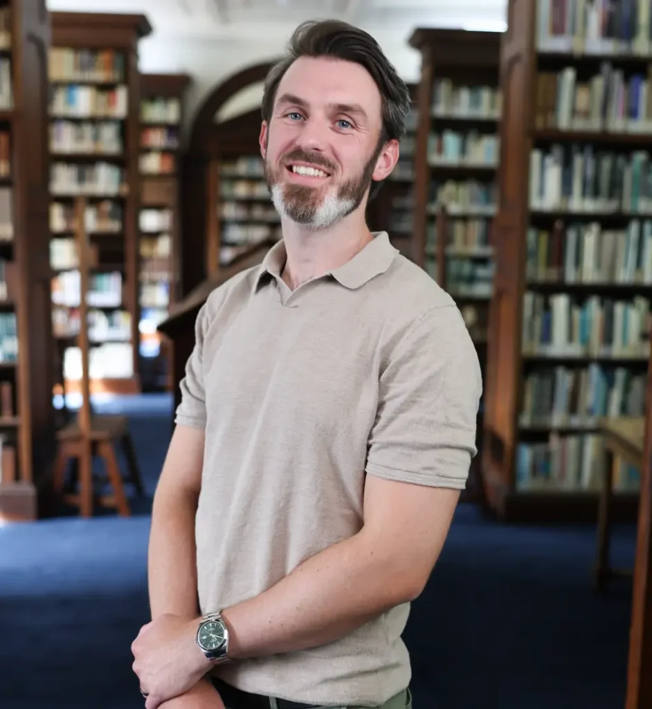 Ryan Hegarty, CBT and EMDR therapist offering online therapy, standing in a library during a professional portrait